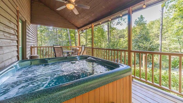 Un bain à remous sur une terrasse en bois, avec vue sur les arbres.