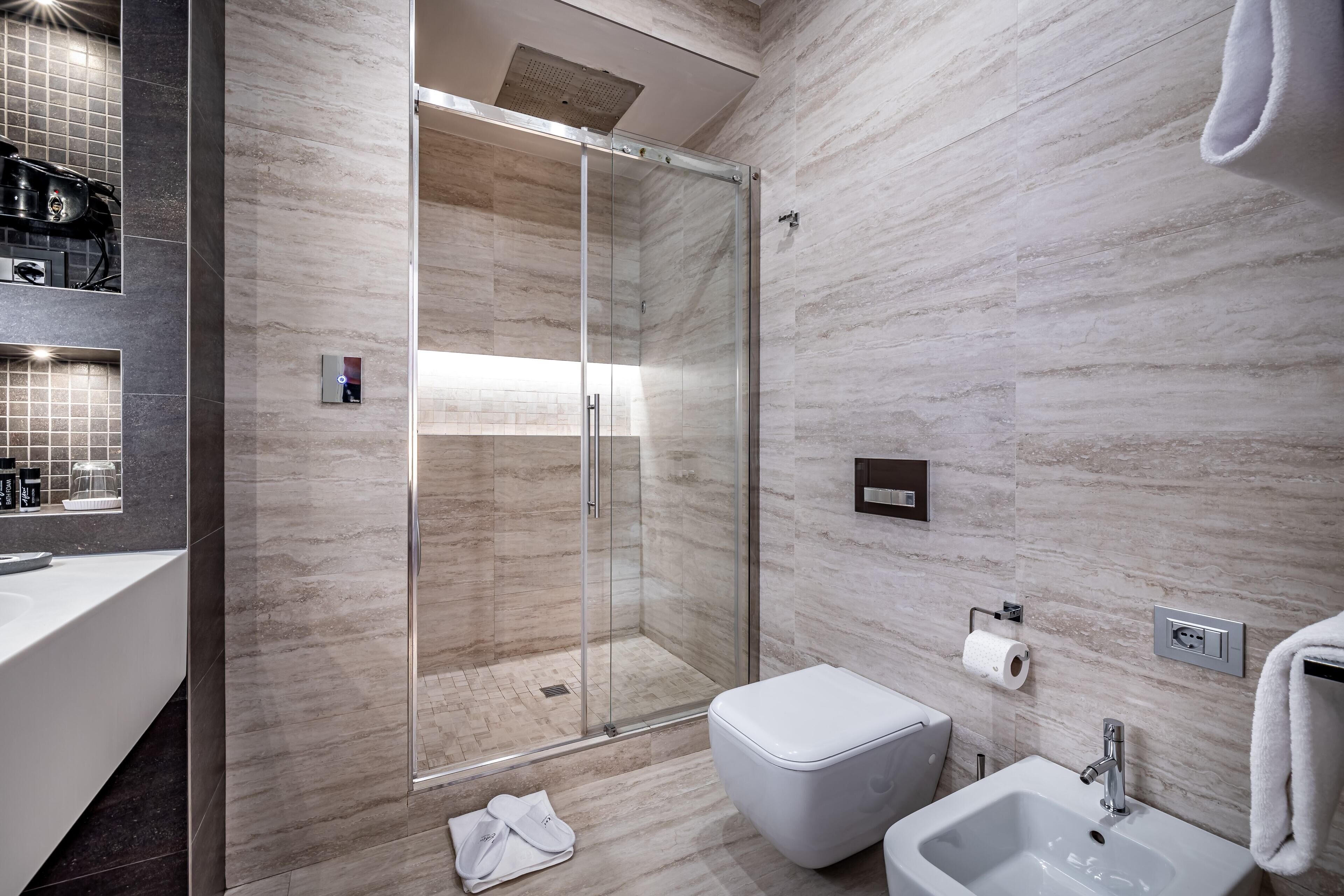 Une salle de bain moderne avec une douche à parois de verre, un lavabo blanc et des toilettes.