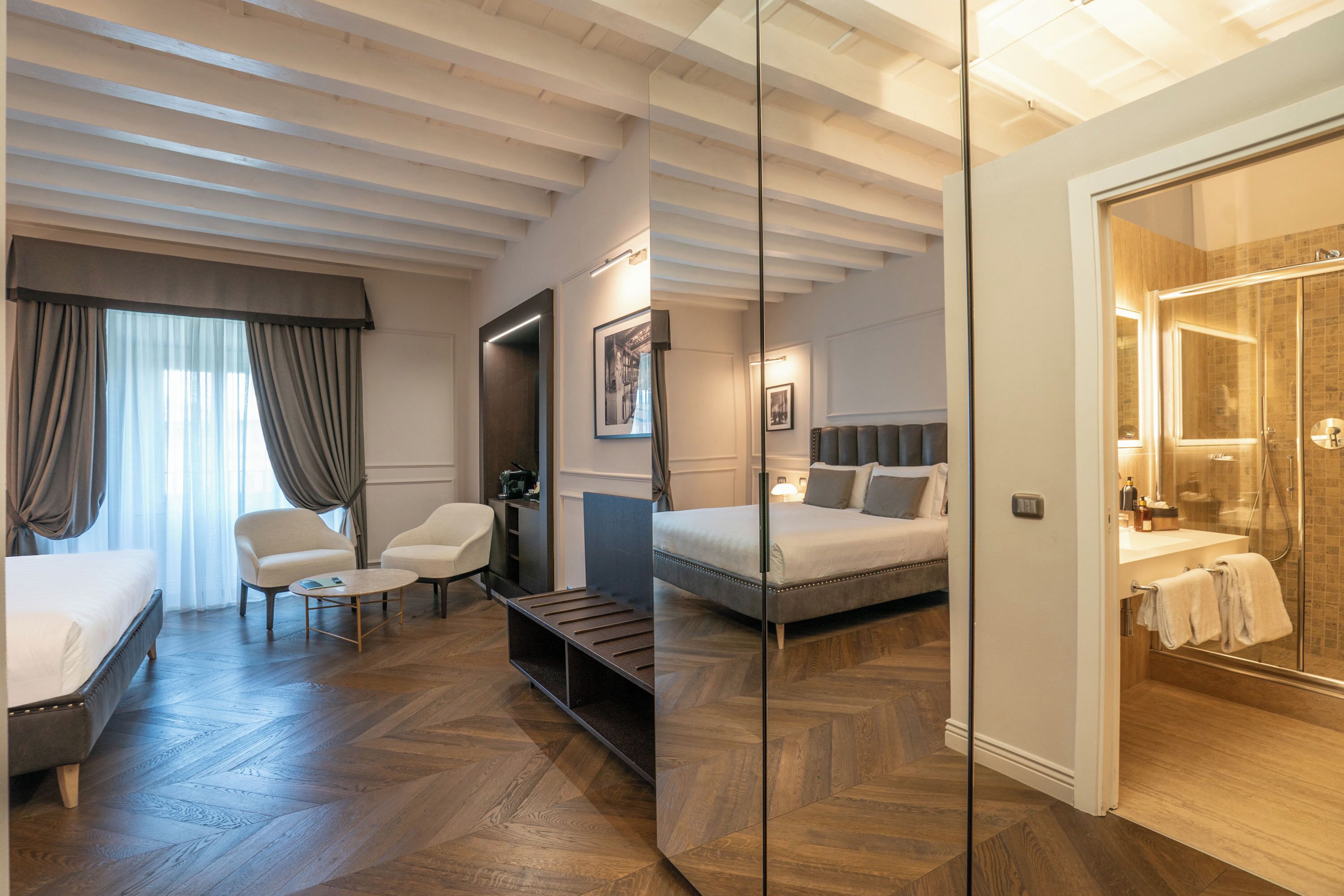 Habitación de hotel con cama, zona de estar, escritorio y cabina de ducha.