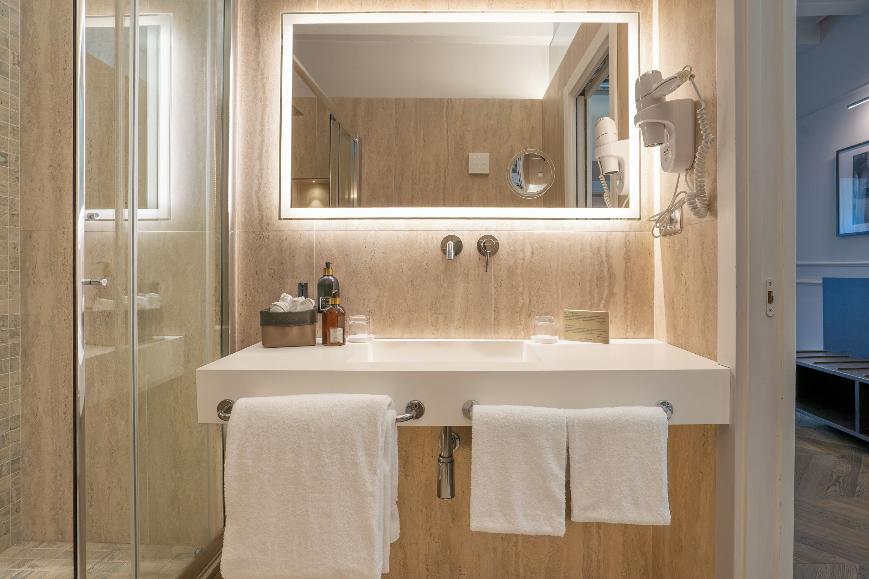 A modern bathroom with a large mirror, two sinks, and a glass shower enclosure.