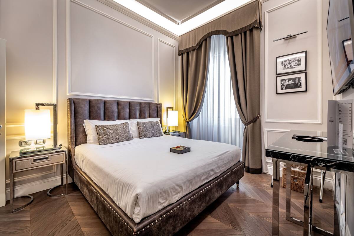 A spacious bedroom with a large bed, bedside tables, a desk, and a wardrobe.
