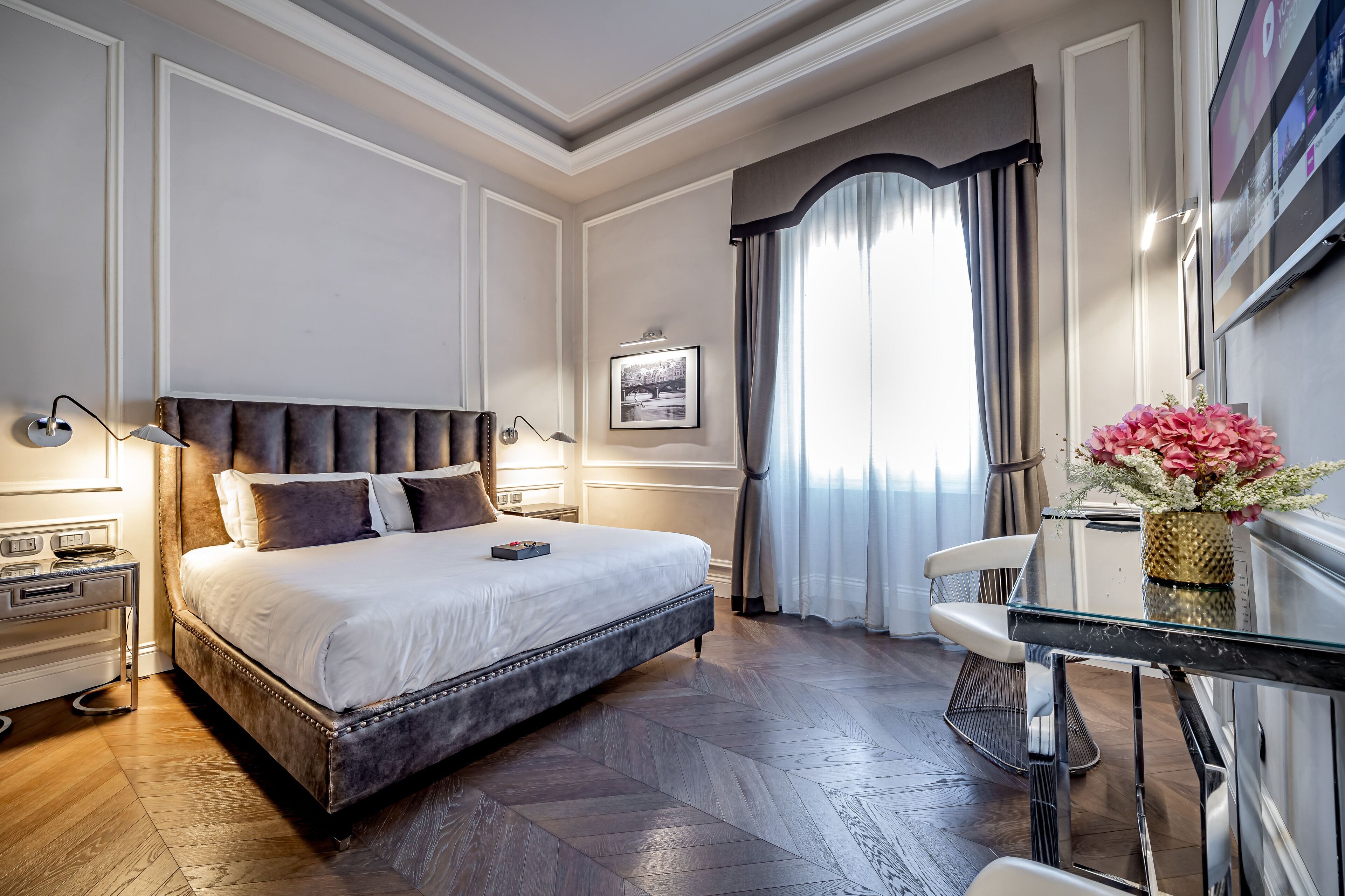 Une chambre d’hôtel avec un grand lit, un bureau avec une chaise, un téléviseur à écran plat et une fenêtre avec des rideaux.