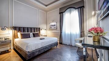 Une chambre d’hôtel avec un grand lit, un bureau avec une chaise, un téléviseur à écran plat et une fenêtre avec des rideaux.
