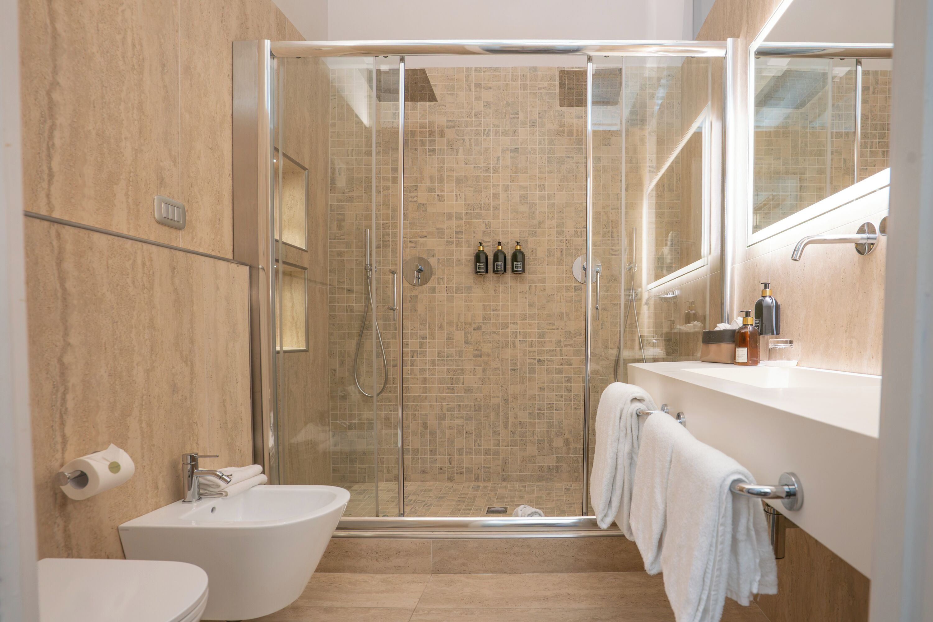 Een moderne badkamer met een glazen douchecabine, een vrijstaand bad, een wastafel en een badkamermeubel met spiegel.