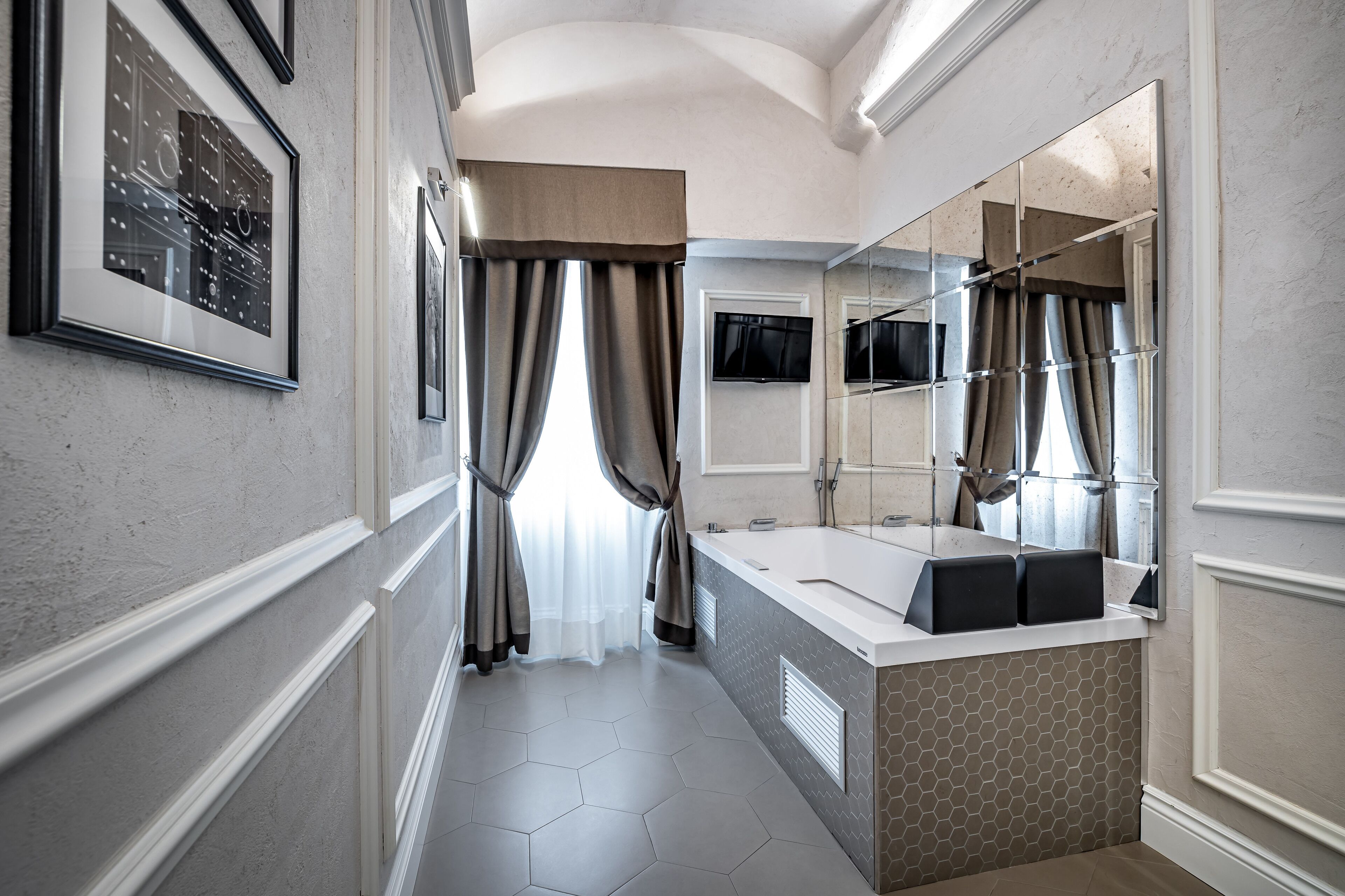 A modern bathroom with a large mirror, a bathtub, and a vanity with a sink.