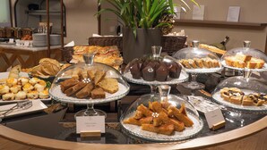 Ein reichhaltiges Buffet mit verschiedenen Speisen, einer Topfpflanze und einer modernen Leuchte.