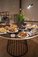 Un tavolo da buffet con diversi cibi, una pianta in vaso e un moderno lampadario.