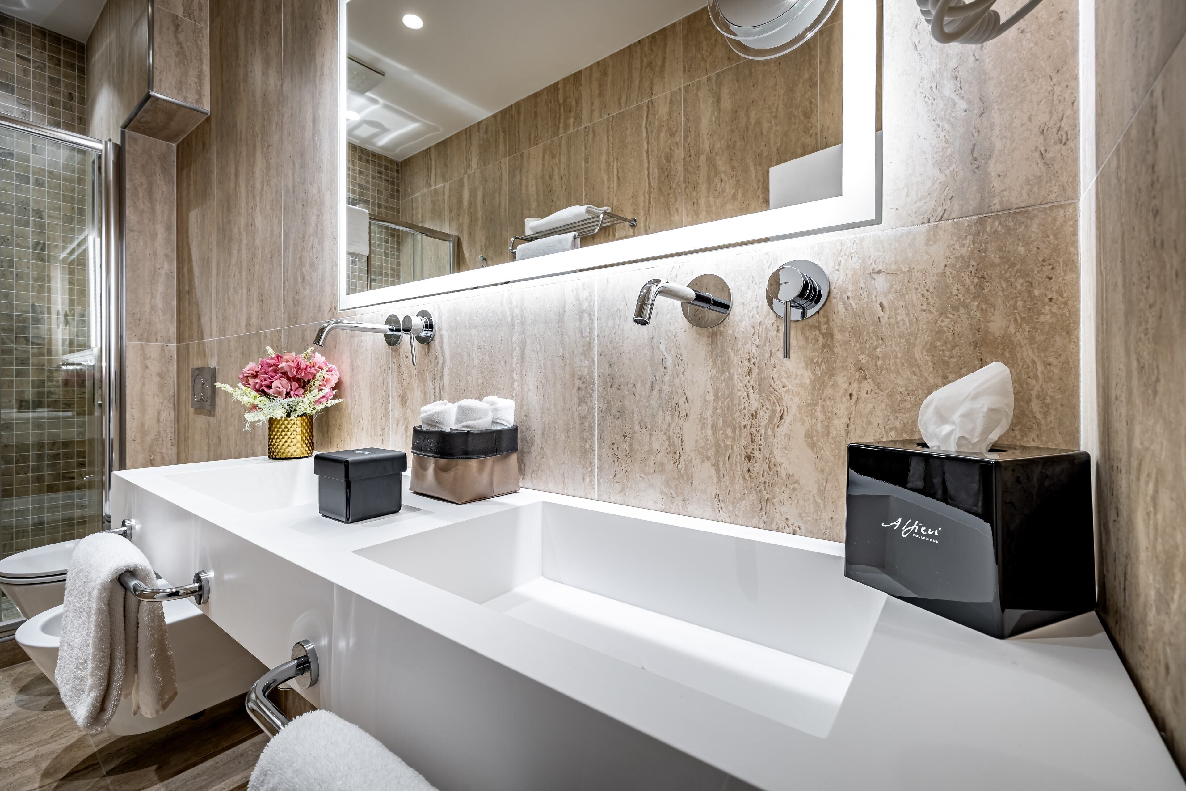 Un baño moderno con un lavamanos grande, un espejo y un perchero para toallas.