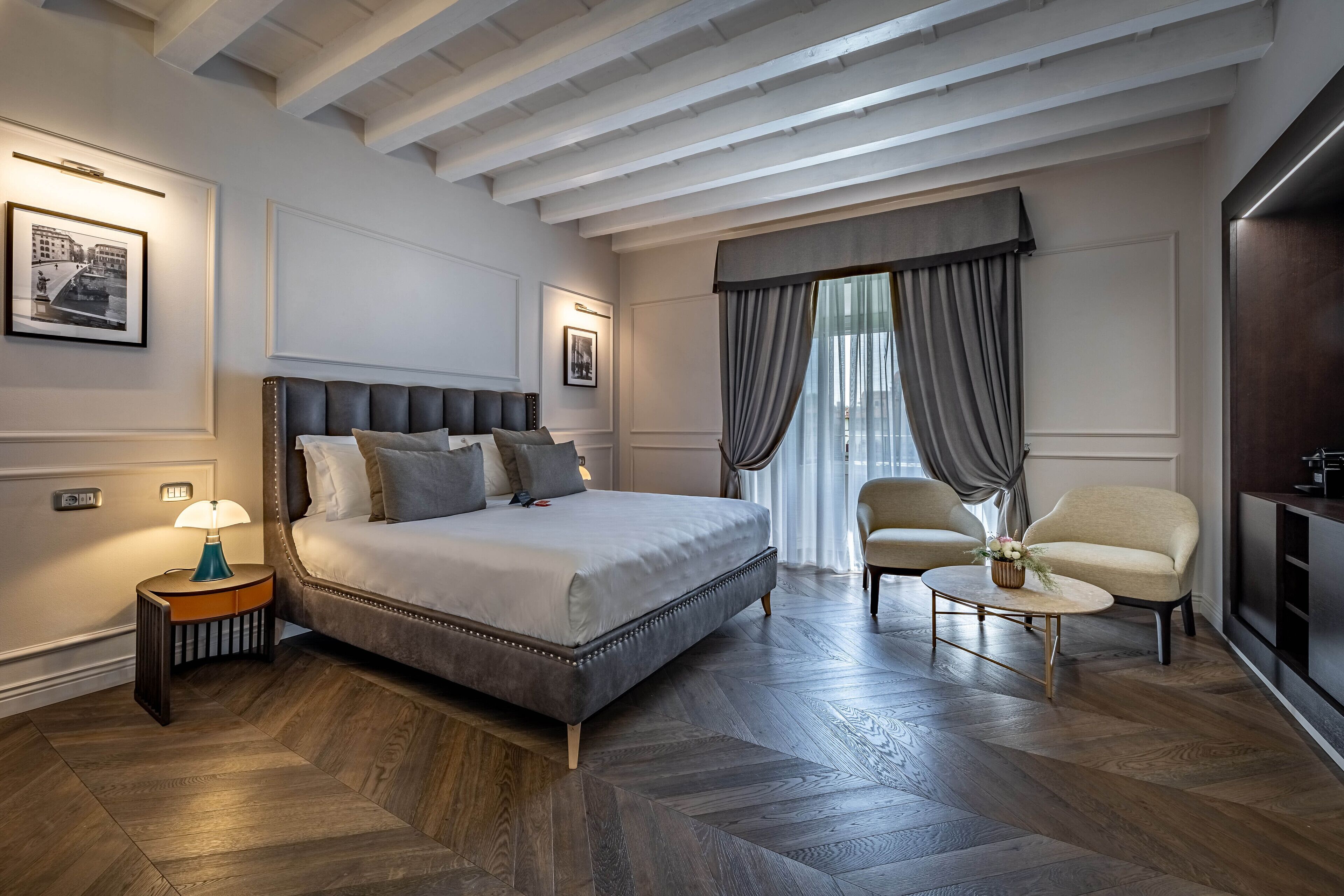 A modern hotel room with a large bed, a small side table, a chair, and a TV.