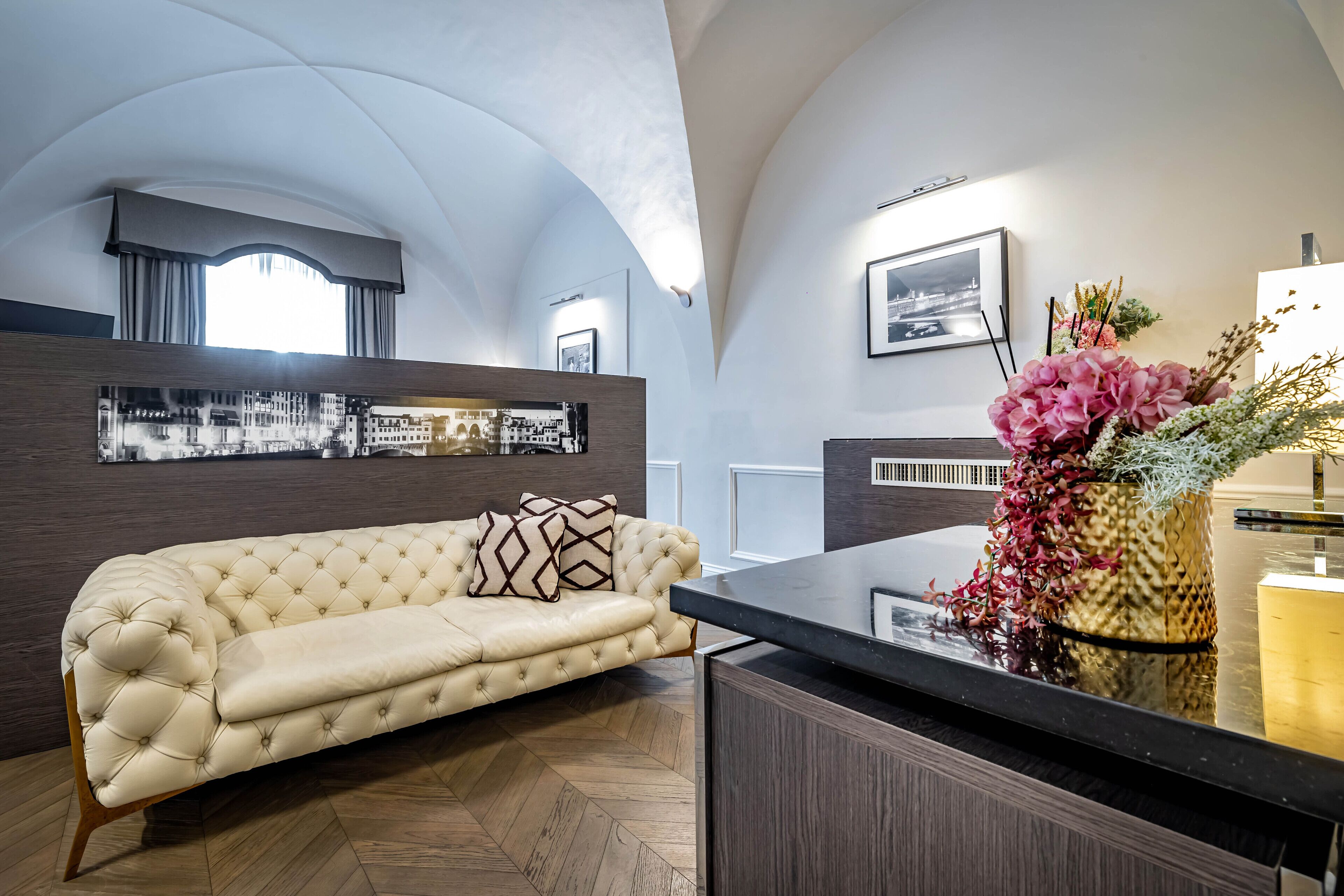 Ein modernes Wohnzimmer mit einer gepolsterten Couch, einer Holzkommode und einer dekorativen Vase mit Blumen.