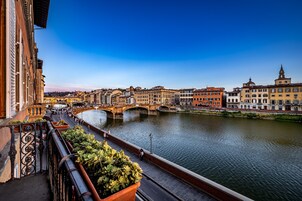 Vista sul fiume con un ponte, edifici e un balcone con piante.