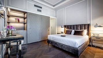 Una habitación de hotel moderna con una cama grande, un escritorio con silla, un armario y una mesita de noche con lámpara.