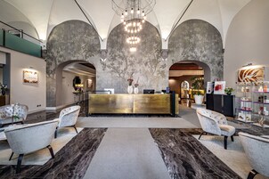 Una hall con reception, zona salotto e un grande lampadario.