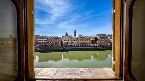 Blick aus einem Fenster auf eine Stadtansicht mit Gebäuden, einem Fluss und blauem Himmel.