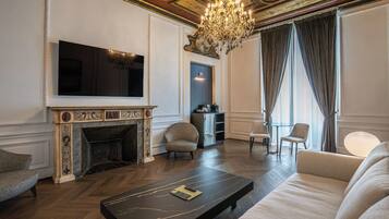 Un salon avec une cheminée, un téléviseur, un lustre et un canapé.