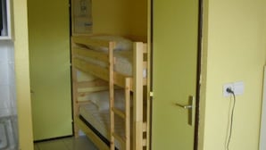 A room with a bunk bed, a door, a wall socket, and a poster on the wall.