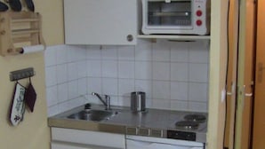 A compact kitchen with a microwave, sink, and a small refrigerator.