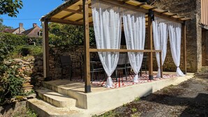 A covered outdoor seating area with stone walls and a pergola structure. - Maison Avec Piscine Dans un Hameau Pour 8 Personnes, Entre Lascaux et Hautefort (GRANGES D ANS)