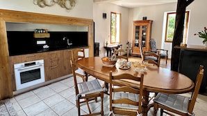 A dining area with a wooden table, chairs, and a cabinet. - Maison Avec Piscine Dans un Hameau Pour 8 Personnes, Entre Lascaux et Hautefort (GRANGES D ANS)