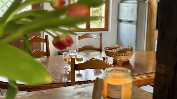 A dining table with chairs, a basket of bread, and a candle. - Maison Avec Piscine Dans un Hameau Pour 8 Personnes, Entre Lascaux et Hautefort (GRANGES D ANS)