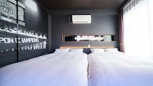 Una habitación de hotel con una cama grande, un televisor montado y un aire acondicionado instalado en la pared.