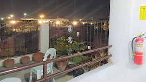 Un balcón con plantas en macetas, una silla blanca y un extintor.
