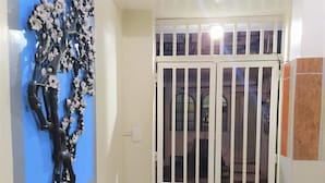 Un pasillo con una puerta blanca, una pared azul y una reja de metal.