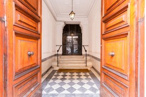 A hallway with wooden doors and a checkered floor leading to a black gate. - SPOTinROME Visconti Architect Home (Roma)