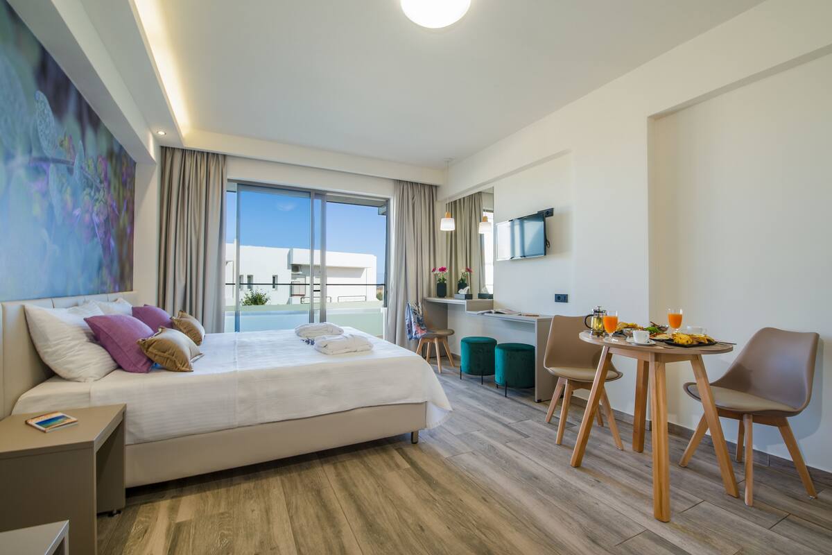 Ett modernt hotellrum med en stor säng, ett skrivbord och en matplats.
