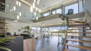 A modern interior with a central reception desk, glass railings, and a spiral staircase.