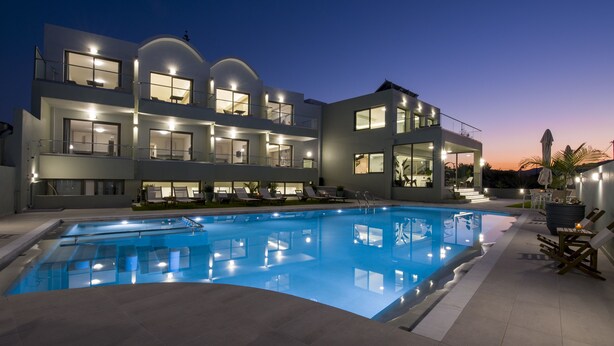 A modern building with a swimming pool, multiple balconies, and outdoor seating areas.