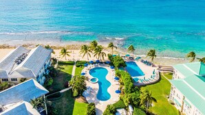 A resort with a large pool area, multiple swimming pools, and a beach. - Ocean Front Luxury Condo Panoramic Views of the Caribbean Sea  (George Town)