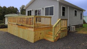 Une maison mobile de plain-pied dotée d’une terrasse en bois et d’un petit porche.