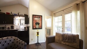 A living room with a sofa, a coffee table, and a kitchen area with cabinets and appliances. - Private Willow Glen Studio Guesthouse (San Jose)