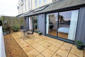 A patio with a table and chairs, a sliding glass door, and a view of the interior.