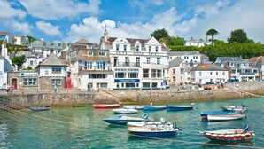 Une ville côtière qui se distingue par un imposant bâtiment blanc portant l’inscription « Ship & Castle Hotel » et où se trouve, à côté, un café appelé « Quayside Cafe ».