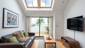 Un salon moderne avec un canapé, une table basse, un téléviseur à écran plat et une lucarne.