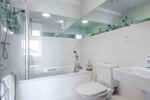 A modern bathroom with a glass-enclosed shower, a white toilet, and a sink.