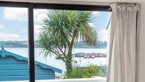 Un balcon avec un lit, une vue sur la mer et un palmier.