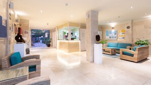 A spacious lobby with a reception desk, seating area, and a view of the outdoor garden.