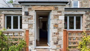 Une maison en pierre avec une porte d’entrée centrale donnant sur l’intérieur.