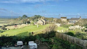 A rural landscape with a grassy field, stone buildings, and a wooden fence.