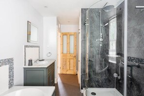 A modern bathroom with a glass-enclosed shower, a white sink, and a wooden door in the background. - Gin O'Clock, Mevagissey, Level Walk to Harbour! (Mevagissey)