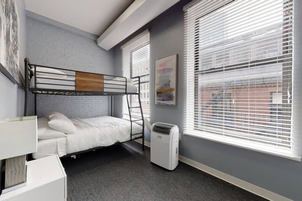 Dormitorio con literas, escritorio, calefacción y ventana con persianas.