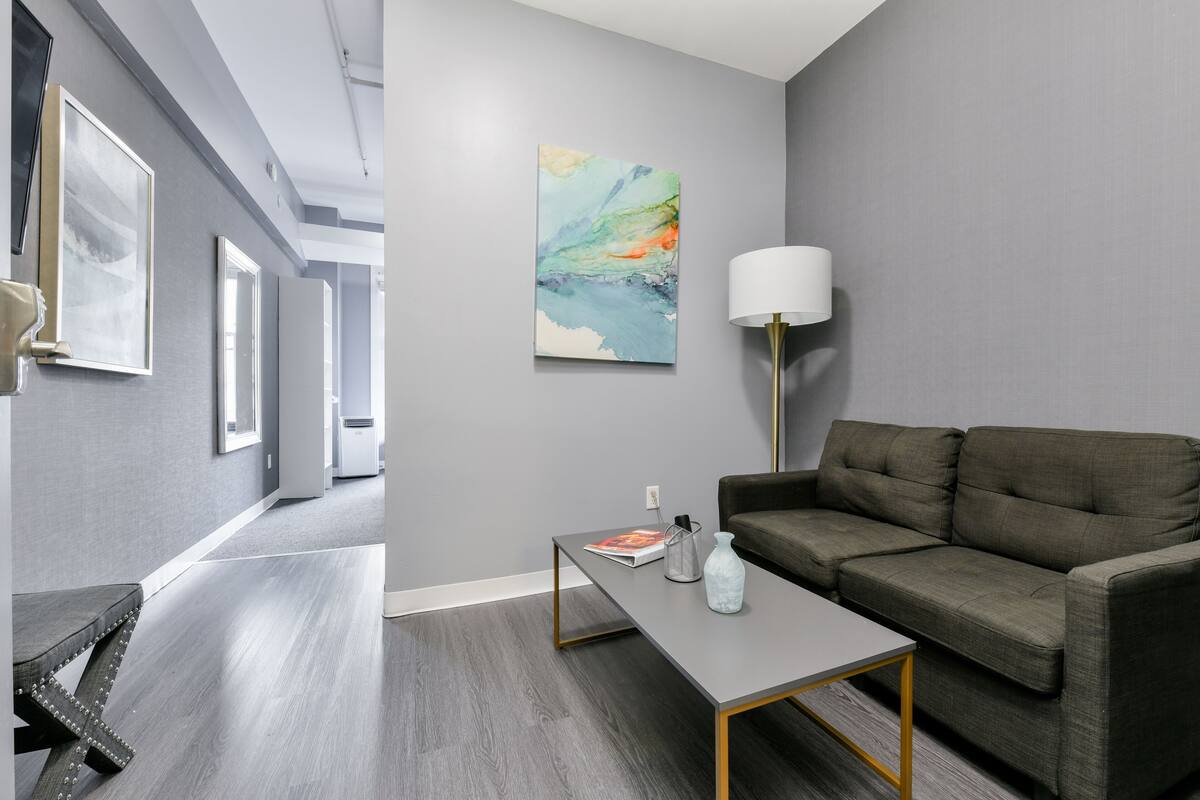 Una sala moderna con un sofá gris, una mesa de centro y una lámpara de pie.