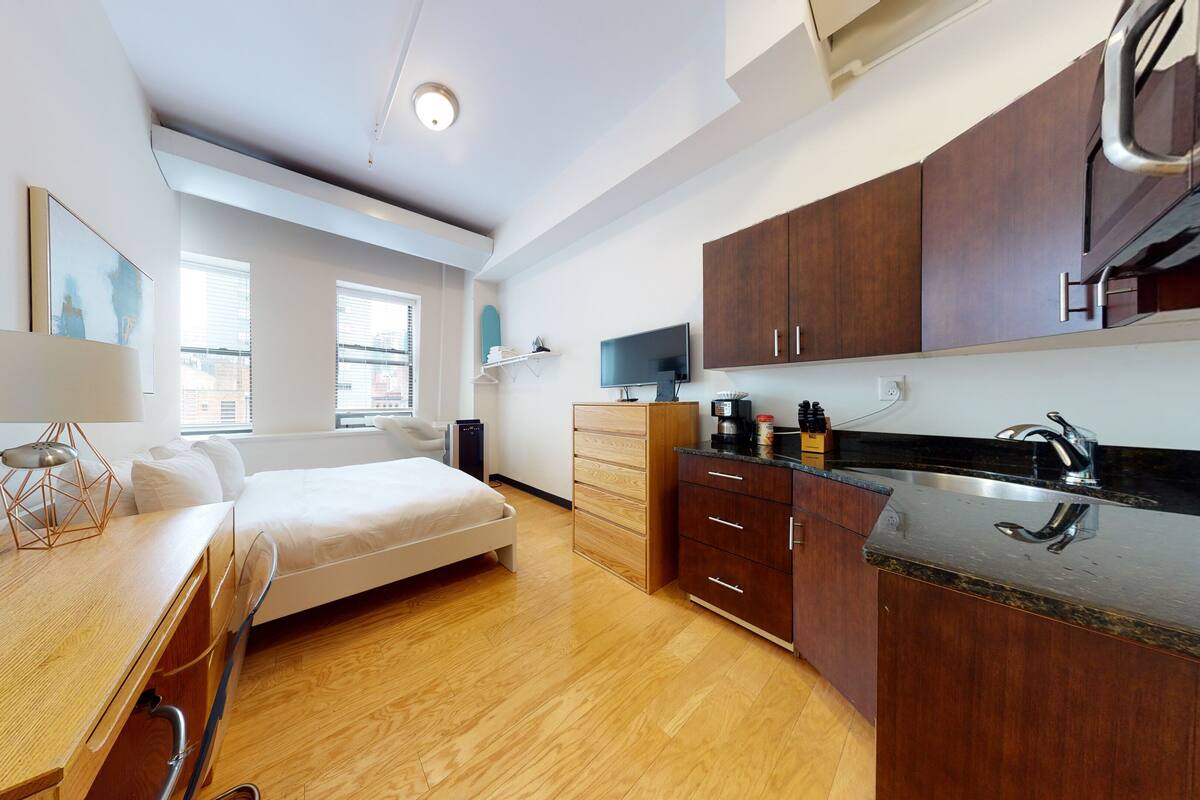 Una habitación de hotel moderna con cama, escritorio y kitchenette.