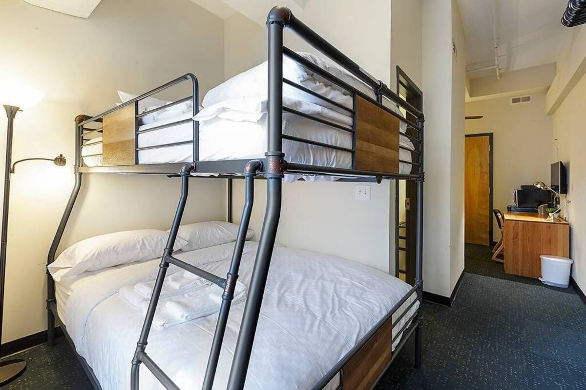 Dormitorio con literas, escritorio, silla, lámpara y televisor.