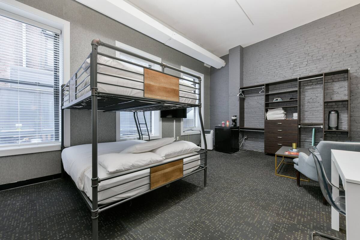 Habitación con literas, escritorio, silla y estantería.