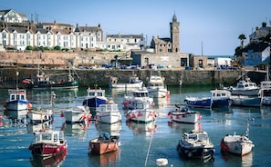 A harbor with various boats docked, a prominent clock tower, and residential buildings along the waterfront. - Homely Cottage with Sun Terrace, Short Walk to Beach (Porthleven)