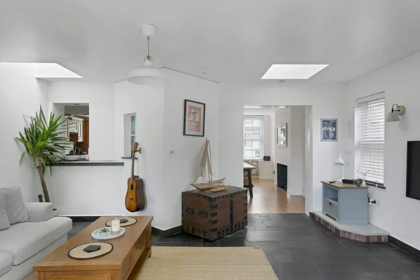 A modern living room with a sofa, coffee table, guitar, and a sailboat model. - Spacious House Large Patio & Free Parking (Barnstaple)